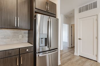 A modern kitchen with a stainless steel refrigerator and wooden cabinets